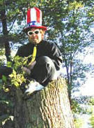 Donnie Love sitting on a tree stump wearing a big tall Uncle Sam hat
